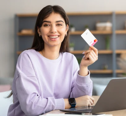 moça sorrindo frente ao notebook utilizando cartão Méliuz